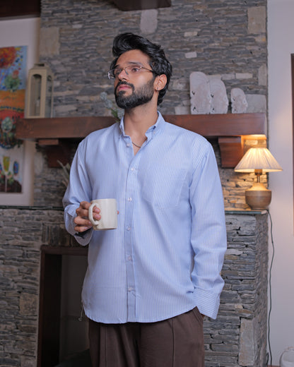 Man holding a mug in a room with stone walls and a lamp.